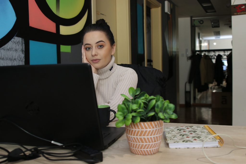 Image represents woman posing in front of her computer in the office space